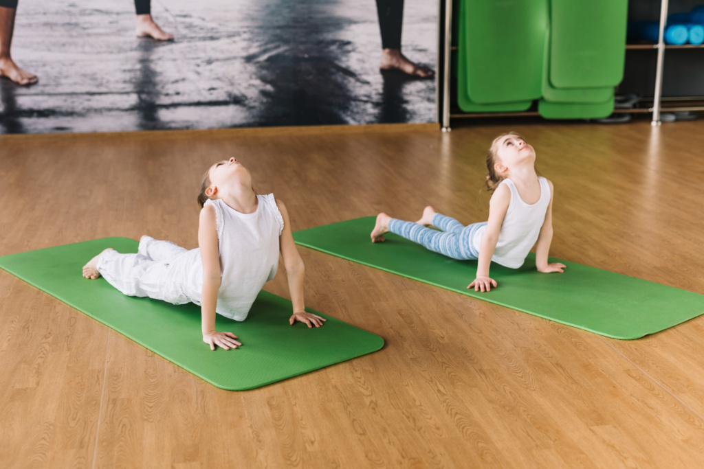 two-healthy-girl-exercising-on-green-mat-over-wooden-desk.jpg