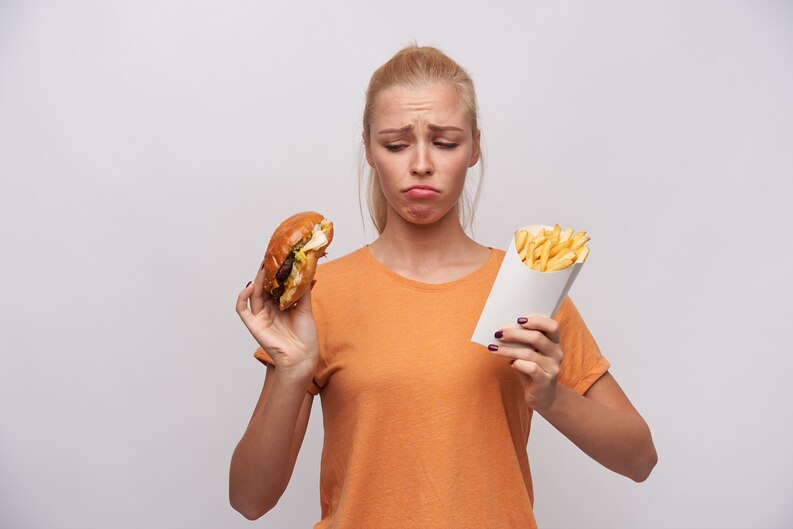 [fpdl.in]_upset-young-pretty-blonde-woman-in-orange-t-shirt-keeping-unhealthy-food-in-her-hands-and-looking-sadly-at-it-frowning-eyebrows-and-twisting-her-mouth-while-posing-over-white-background_295783-6669_medium.jpg